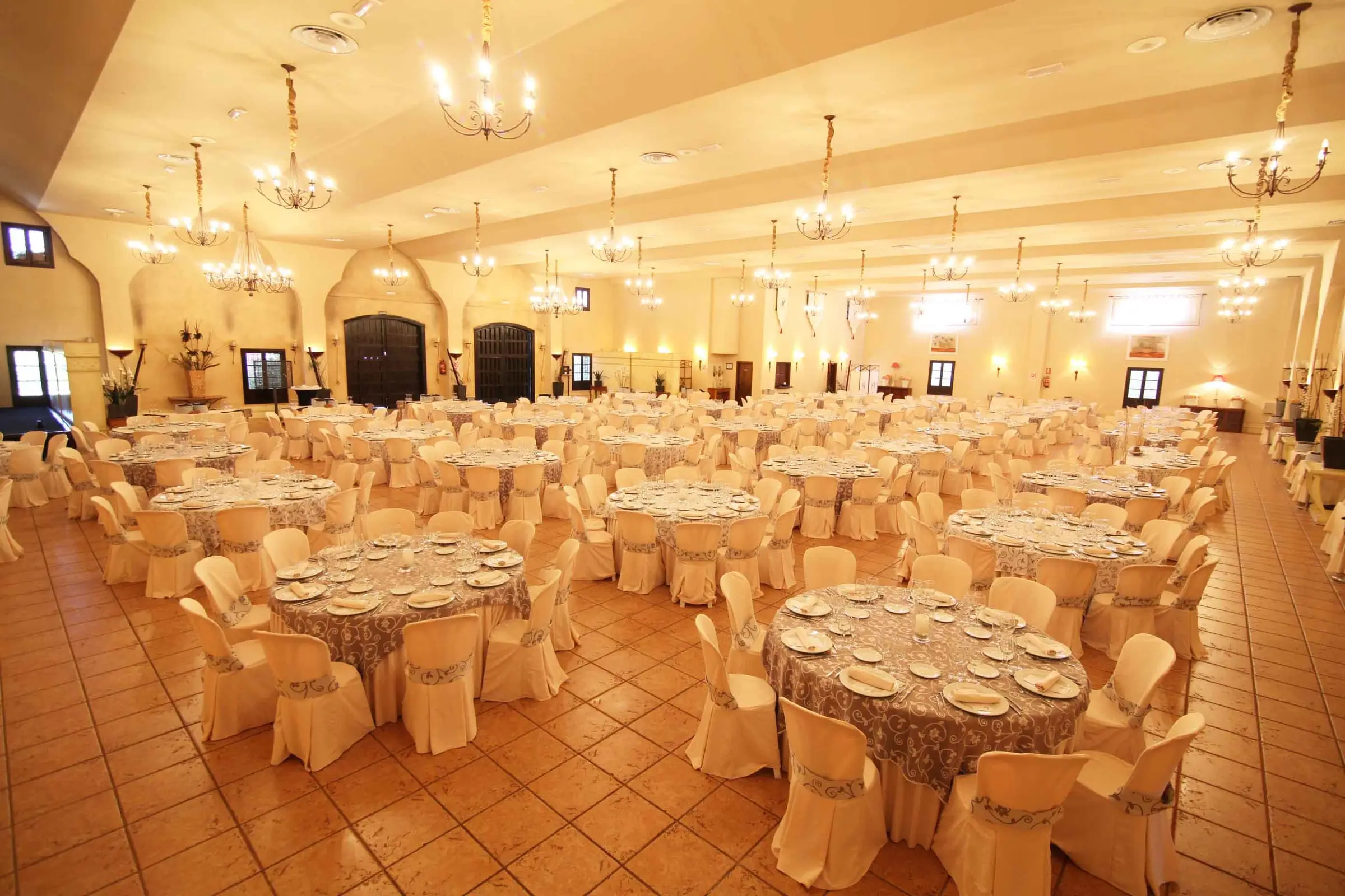 El gran salón montado para un banquete, con arcos, lámparas de araña y suelo de barro